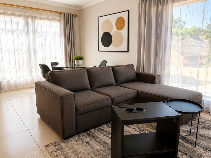 A bright and spacious living area featuring large sliding glass doors, neutral tiled flooring, and modern finishes, offering a comfortable and well-lit living space.