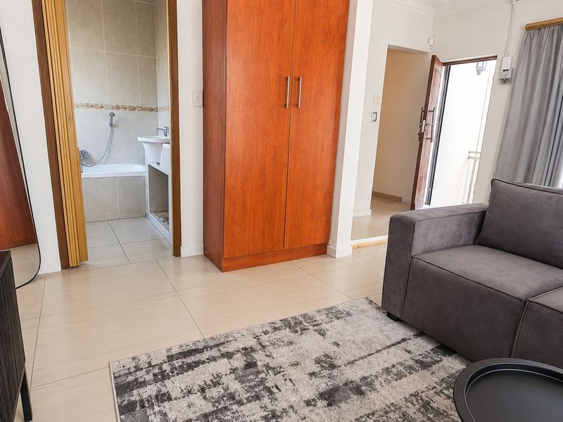 A bedroom featuring tiled flooring, a built-in wardrobe, and an adjoining en-suite bathroom with a bathtub.