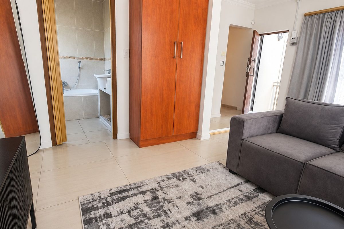 A bedroom featuring tiled flooring, a built-in wardrobe, and an adjoining en-suite bathroom with a bathtub.