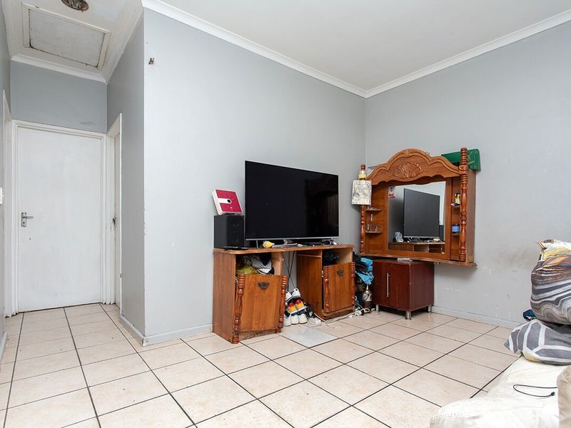 A living area featuring tiled flooring, neutral wall paint, and a ceiling access hatch, requiring minor cosmetic updates to improve its overall presentation.