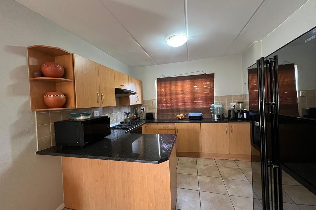 Functional kitchen featuring laminate cabinetry, granite countertops, tiled backsplash, and ceramic flooring, offering a practical layout for daily meal preparation.
