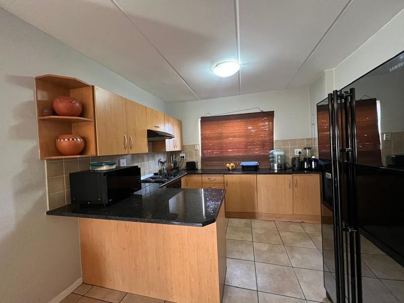 Functional kitchen featuring laminate cabinetry, granite countertops, tiled backsplash, and ceramic flooring, offering a practical layout for daily meal preparation.