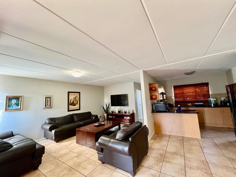 Open-plan living area featuring tiled flooring and a functional kitchen with built-in cabinetry and countertops, creating a cohesive and practical living space.