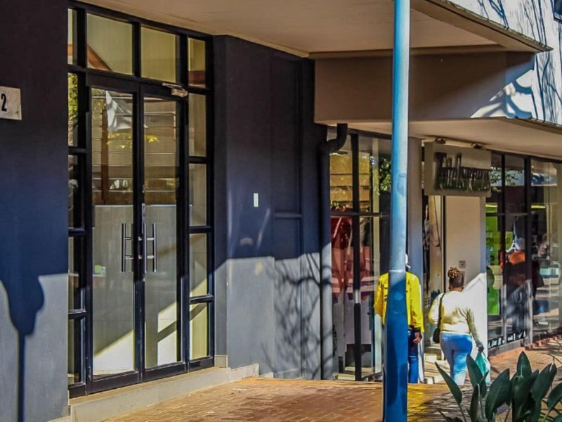 Commercial storefront entrance with large glass display windows and a covered walkway, providing clear access for customers.