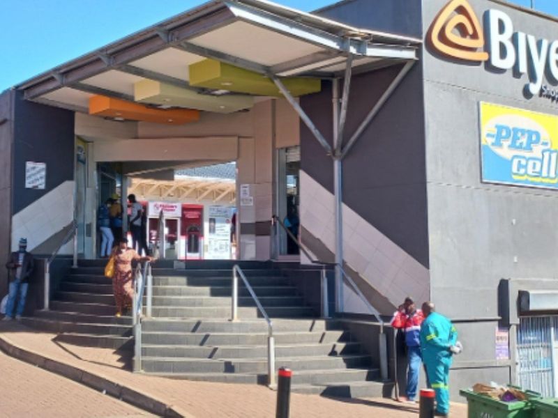 Front entrance of the Biyela Shopping Centre featuring a covered canopy, concrete staircase with metal handrails, and prominent commercial signage.