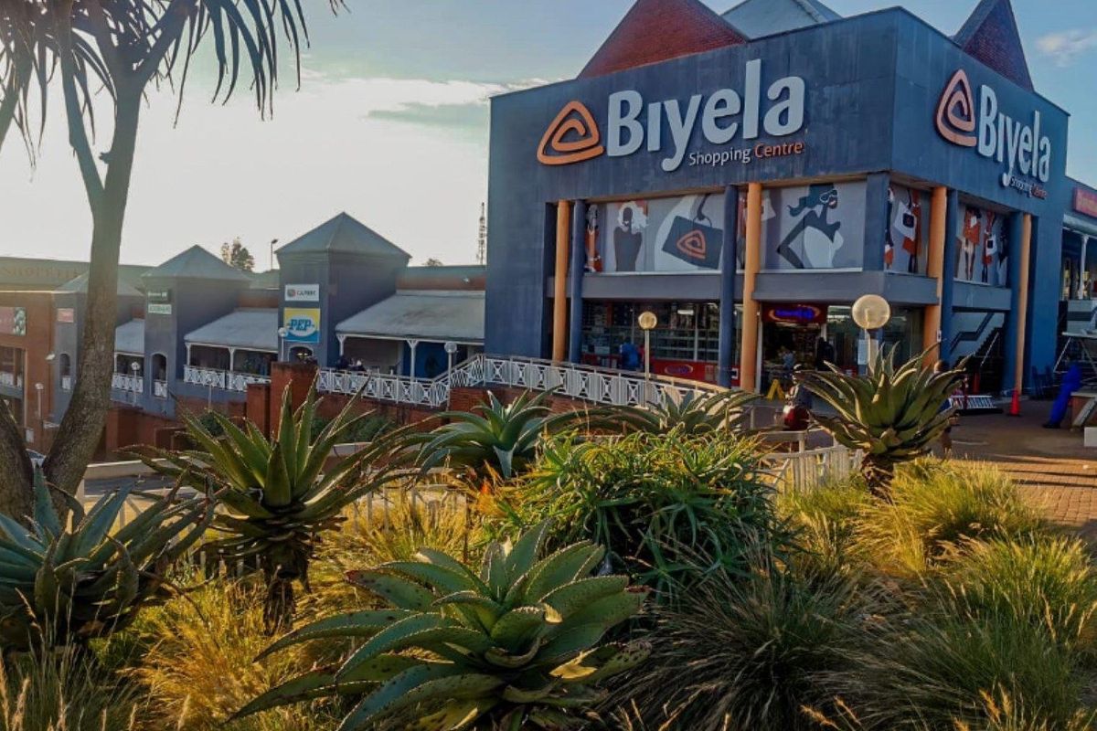 Exterior view of the Biyela Shopping Centre featuring a prominent facade, paved walkways, and landscaped garden areas.