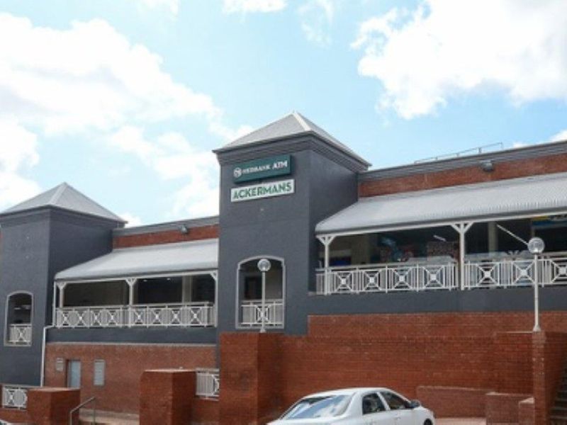 Front elevation of a commercial retail center featuring brick construction, covered walkways, and prominent signage for multiple retail tenants.