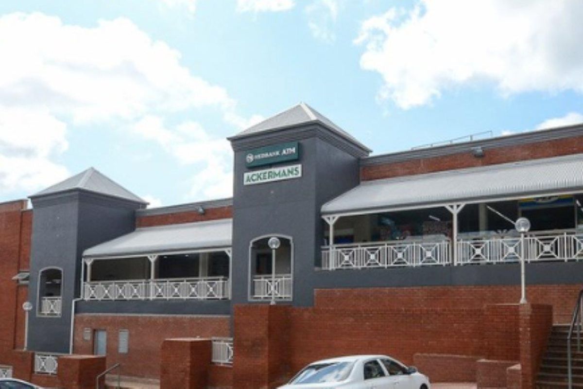 Front elevation of a commercial retail center featuring brick construction, covered walkways, and prominent signage for multiple retail tenants.