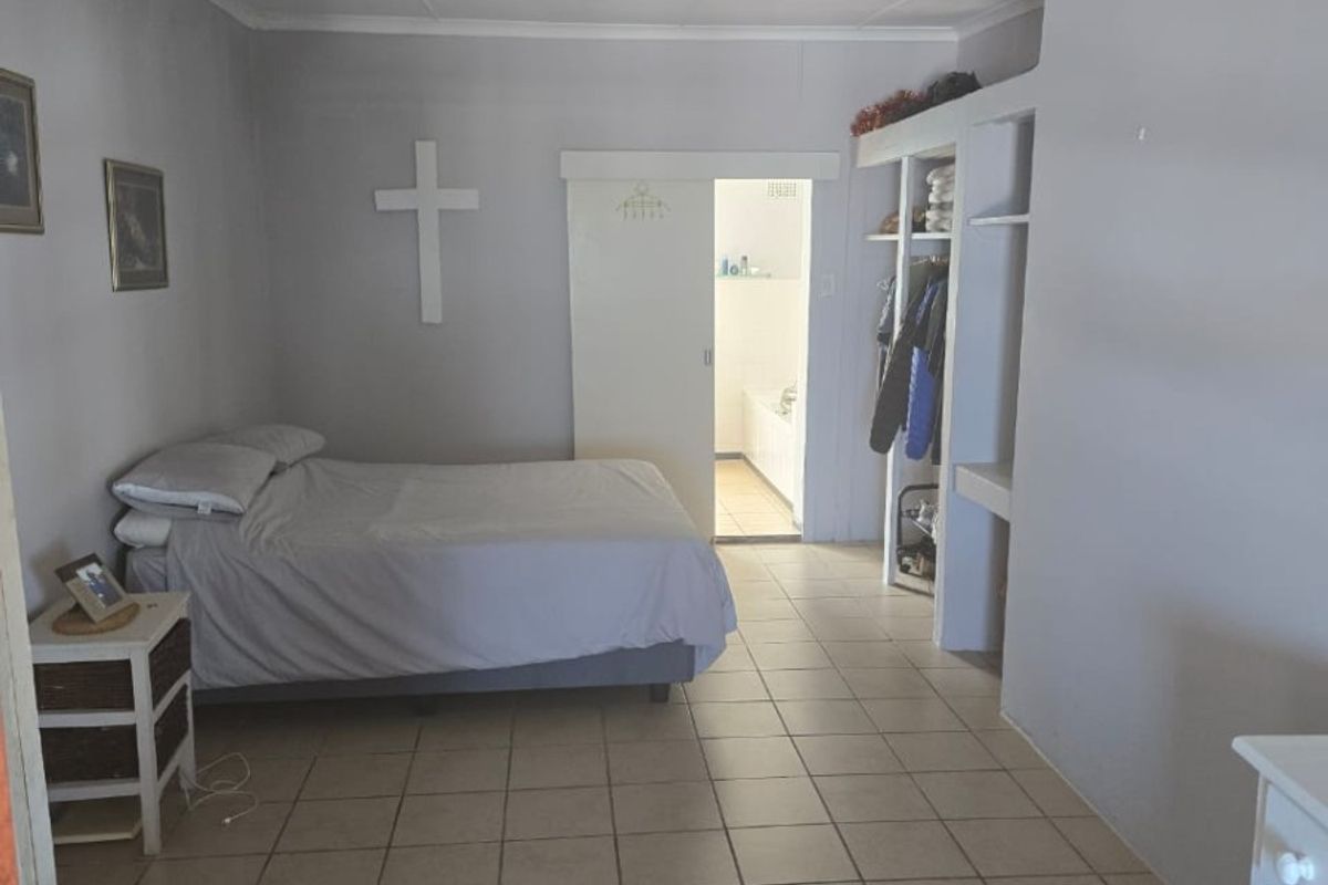 A bedroom featuring ceramic floor tiles, built-in shelving, and an en-suite bathroom access via a sliding door.