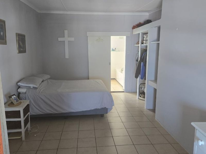 A bedroom featuring ceramic floor tiles, built-in shelving, and an en-suite bathroom access via a sliding door.