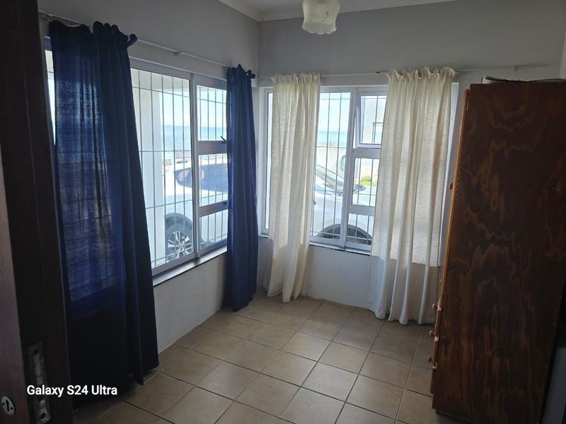 A simple, tiled bedroom featuring large windows with security bars, offering a functional space ready for personalization.