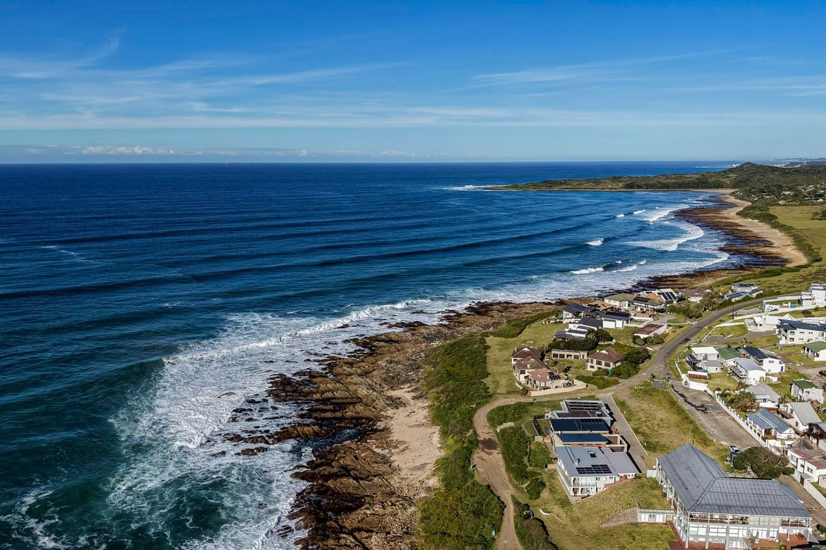 An aerial view of a coastal residential estate situated along the rocky shoreline, showcasing the proximity to the ocean and surrounding landscape.