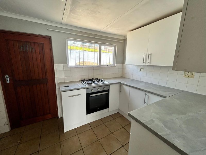 A functional kitchen featuring built-in cabinetry, a gas hob, an oven, tiled backsplash, and tiled flooring.