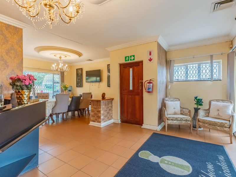 Spacious entrance area featuring tiled flooring, decorative ceiling details, and integrated security features, leading into an open-plan dining space.