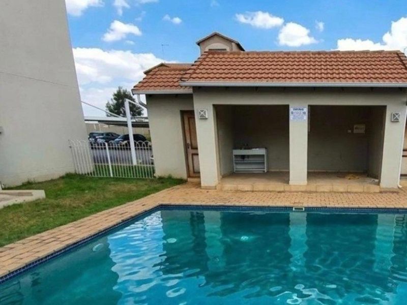Communal swimming pool area featuring a paved deck and a covered patio structure with tiled roofing.