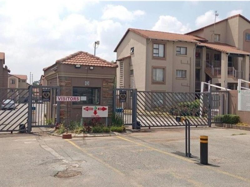 The secure entrance to the apartment complex features a guard house, automated security gates, and electric fencing for controlled access.