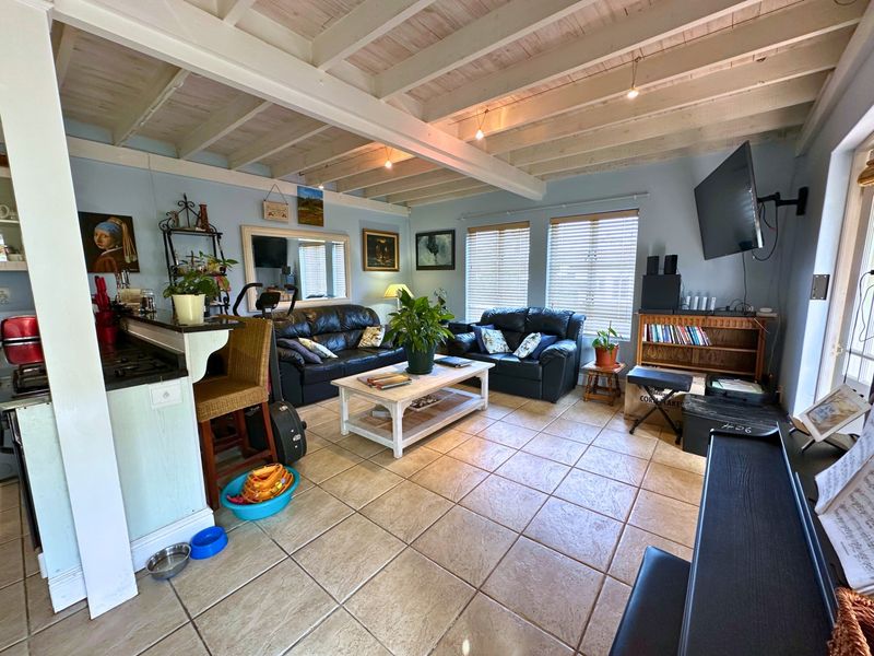 Spacious open-plan living area featuring exposed beam ceilings, ceramic tile flooring, and a functional breakfast bar connecting to the kitchen space.