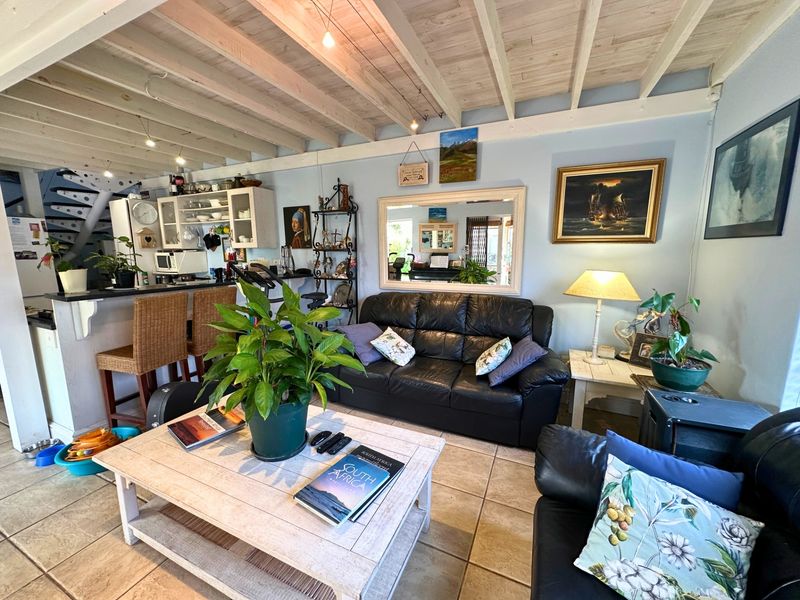 Open-plan living area featuring tiled floors, exposed timber beam ceilings, and an integrated kitchen with a breakfast bar and spiral staircase access.