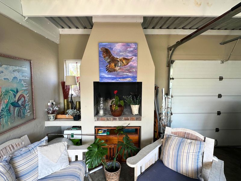 A garage space featuring a built-in fireplace and exposed beam ceiling, currently utilized as a multi-purpose living area.