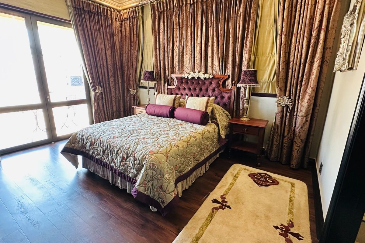 A well-maintained bedroom featuring dark hardwood flooring, crown molding, and a large sliding glass door providing access to the exterior.
