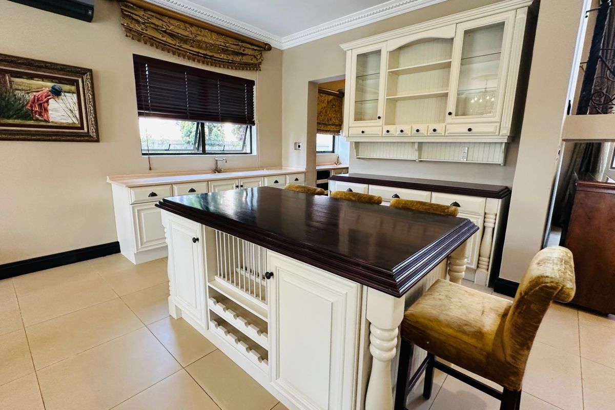A classic kitchen featuring a large central island with a dark wood countertop, extensive built-in cabinetry, and tiled flooring.