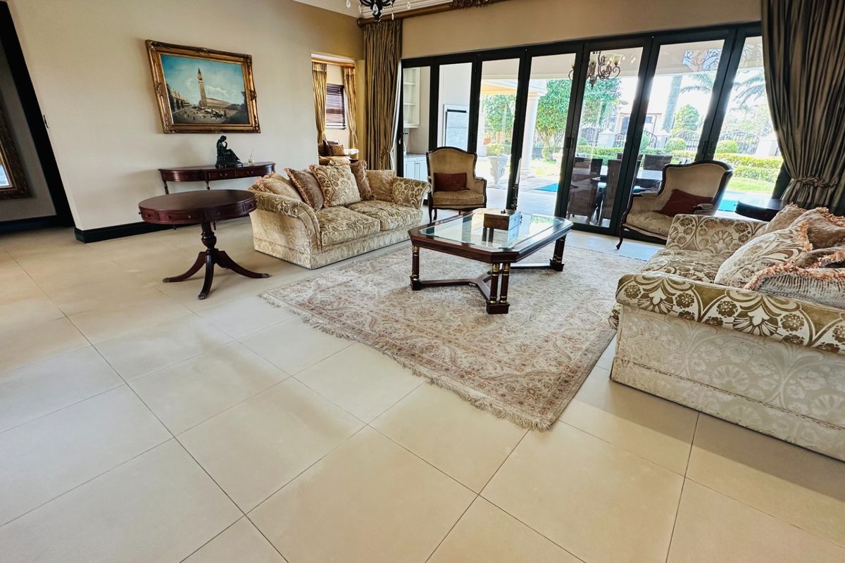 Spacious living room featuring large format floor tiles and expansive sliding glass doors that provide seamless access to the outdoor patio and pool area.
