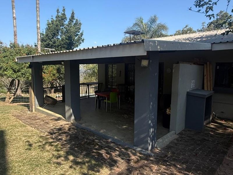 A covered outdoor patio area featuring concrete pillars and a brick-paved walkway, providing a functional space for outdoor living and entertaining.