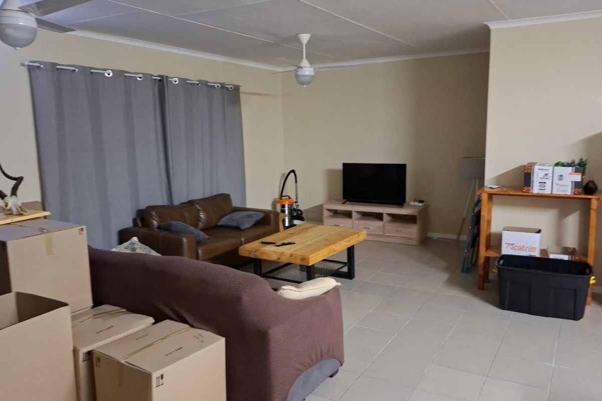 A living room area featuring tiled flooring, ceiling fans, and coved cornicing, currently used as a living space.