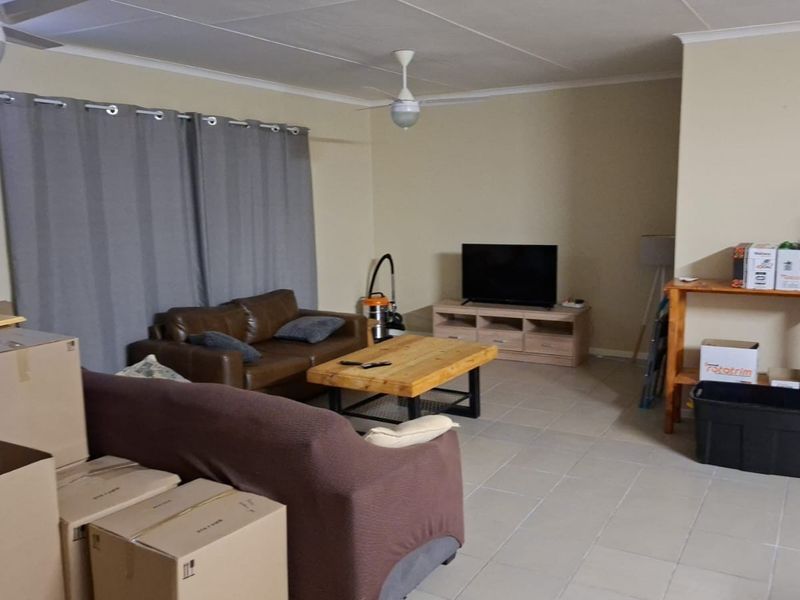 A living room area featuring tiled flooring, ceiling fans, and coved cornicing, currently used as a living space.