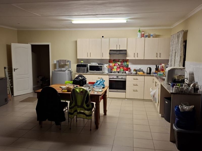 Spacious kitchen featuring light-toned built-in cabinetry, granite countertops, a gas hob, and an integrated oven, offering a functional layout for daily cooking.
