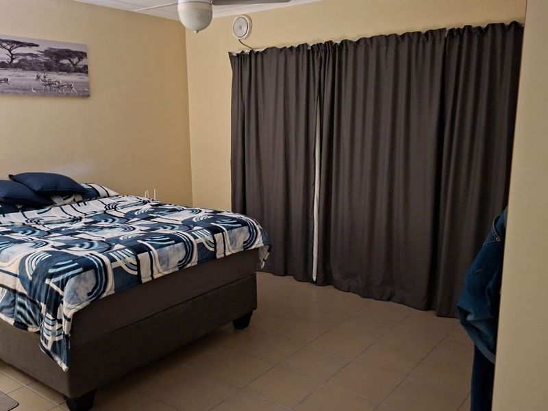 A functional bedroom featuring tiled flooring and a ceiling fan, providing a neutral base for personalization.