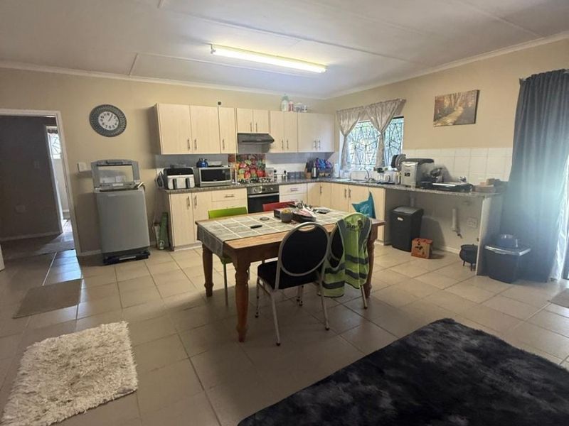 Open plan kitchen and living area featuring tiled flooring, built-in cabinetry, and a functional layout suitable for modern updates.