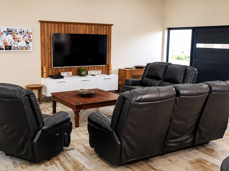 A well-maintained living room featuring timber wall paneling, tiled flooring, and a large sliding glass door providing natural light.