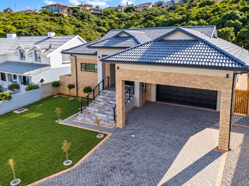 Modern single-story residence featuring a brick facade, tiled roof, paved driveway, double garage, and landscaped front garden with stone-clad entrance stairs.
