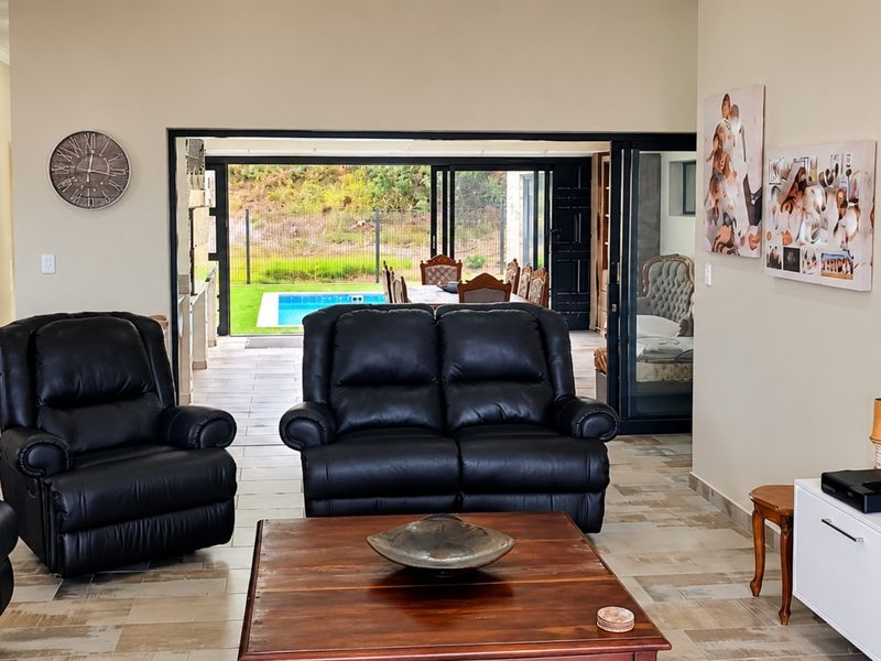 Spacious open-plan living area featuring tiled floors and large sliding glass doors that provide seamless access to the outdoor patio and pool area.