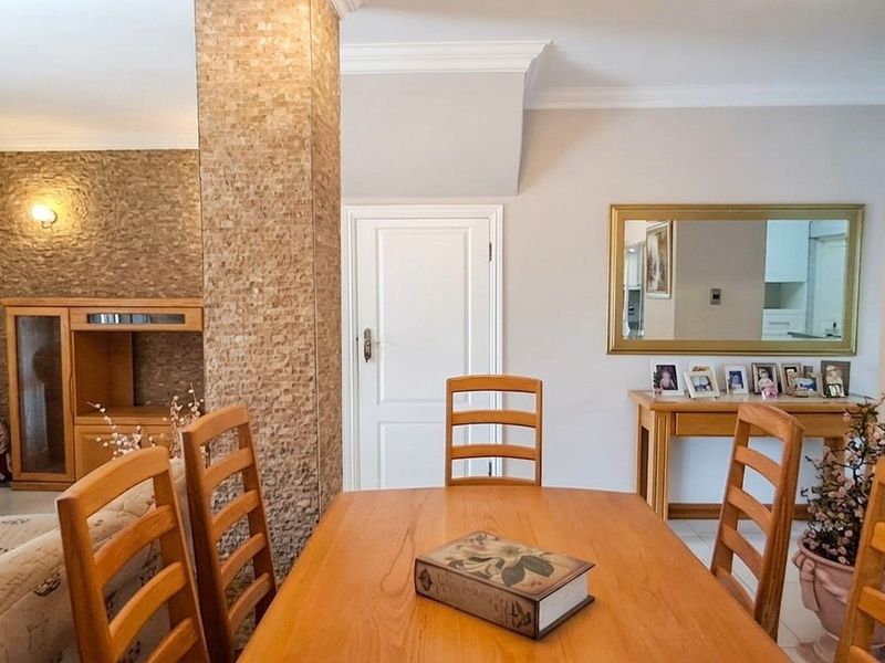 Open-plan living and dining area featuring a distinctive stone-clad feature pillar, crown molding, and neutral tiled flooring throughout.