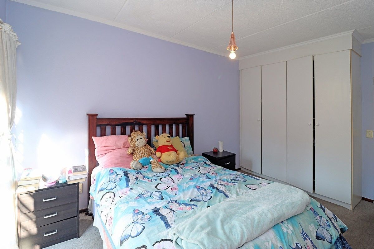 A bedroom featuring a built-in wardrobe, pendant lighting, and carpeted flooring, providing a functional space with neutral wall finishes.