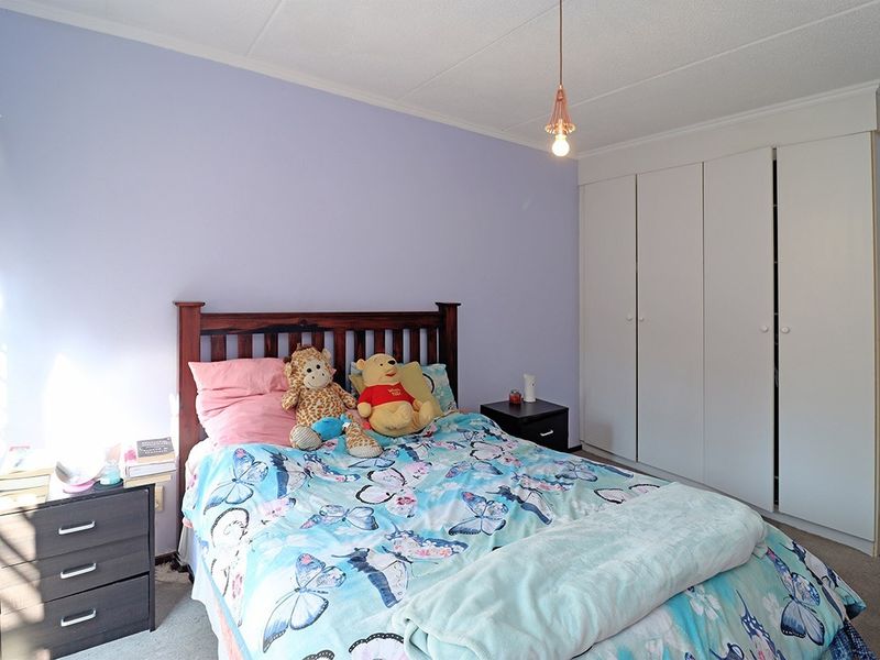 A bedroom featuring a built-in wardrobe, pendant lighting, and carpeted flooring, providing a functional space with neutral wall finishes.
