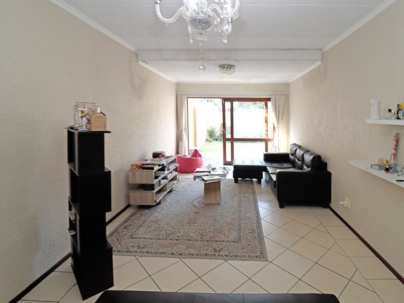Living room featuring tiled flooring and a sliding glass door leading to the exterior, with visible signs of wall and ceiling wear.