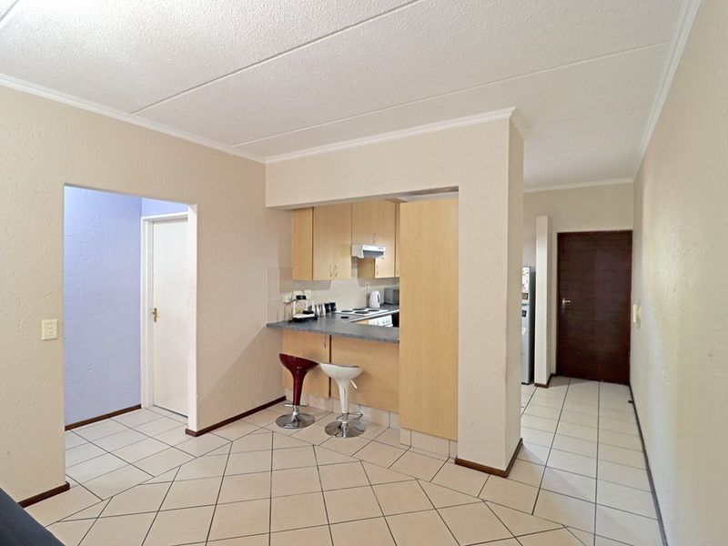 Open-plan living area featuring a compact kitchen with built-in cabinetry, laminate countertops, and ceramic floor tiles throughout the space.