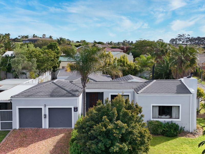 Aerial view of a well-maintained single-story residential property featuring a double garage, tiled roof, and paved driveway in a suburban setting.
