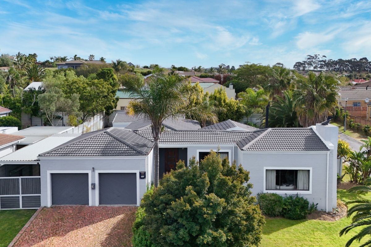 Aerial view of a well-maintained single-story residential property featuring a double garage, tiled roof, and paved driveway in a suburban setting.