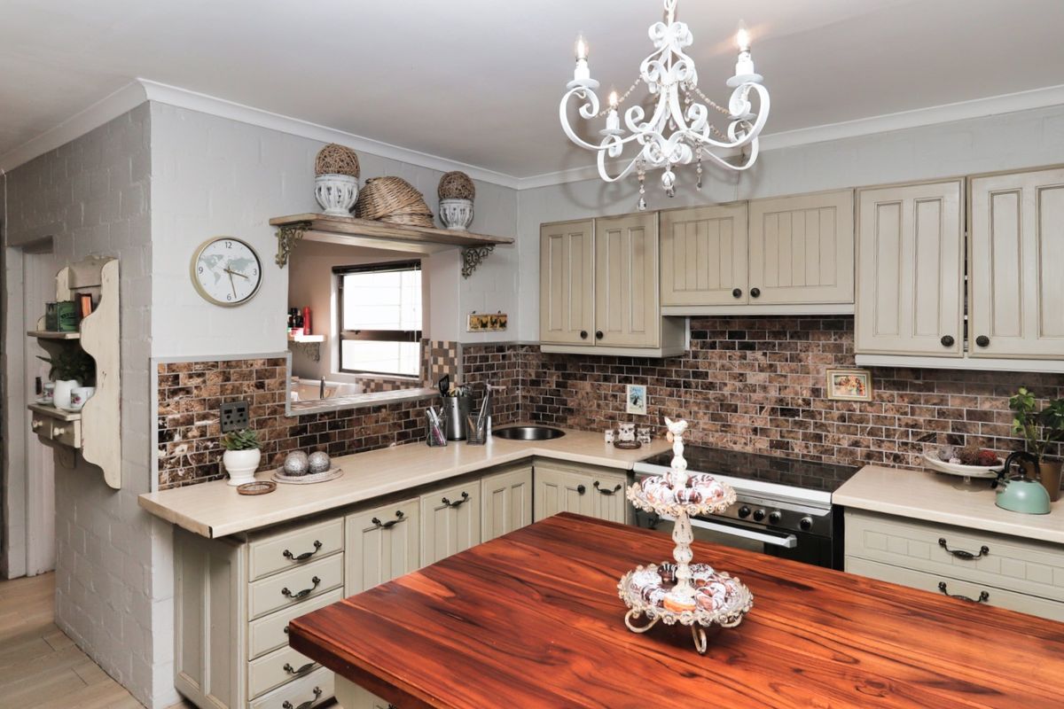 A functional kitchen featuring classic cabinetry, a tiled backsplash, built-in oven and stove, and a central wooden island bench.
