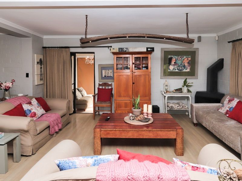 Spacious living room featuring laminate flooring, exposed brick walls, and a wood-burning fireplace, creating a warm and inviting atmosphere.