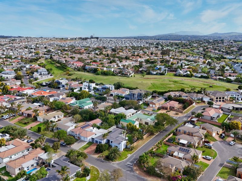 An aerial view of a residential suburb showcasing the surrounding neighborhood, road layout, and local green spaces.
