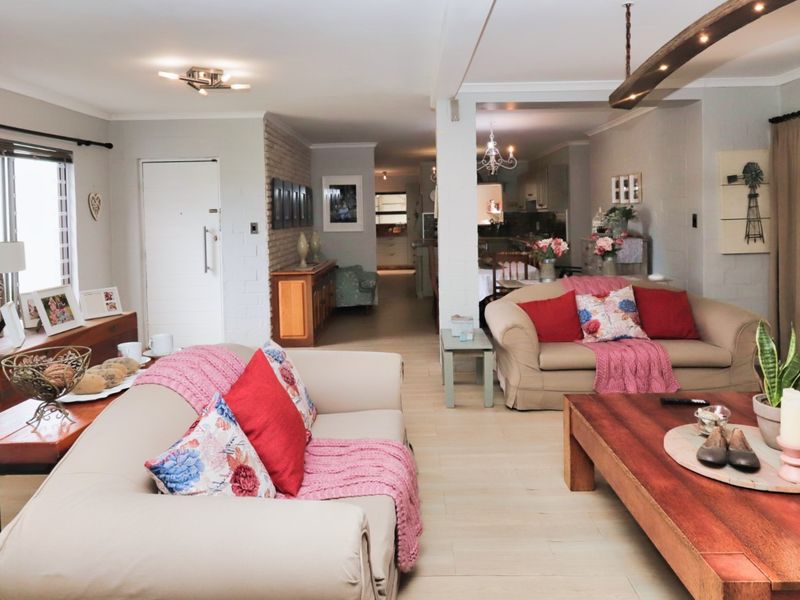 Spacious open-plan living area featuring light-toned tiled flooring, exposed brick accents, and a timber ceiling beam, creating a warm and inviting atmosphere.