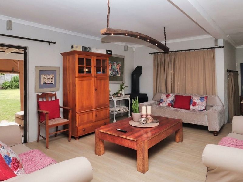 A comfortable living room featuring laminate flooring, a wood-burning fireplace, and direct access to the rear garden through a sliding glass door.