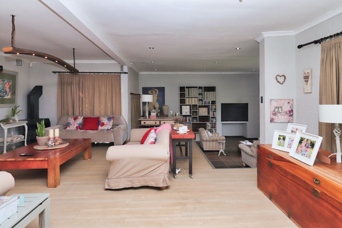 Spacious open-plan living area featuring light laminate flooring, recessed downlighting, and a cozy fireplace, offering a versatile layout for comfortable family living.