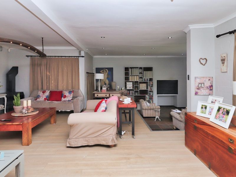Spacious open-plan living area featuring light laminate flooring, recessed downlighting, and a cozy fireplace, offering a versatile layout for comfortable family living.