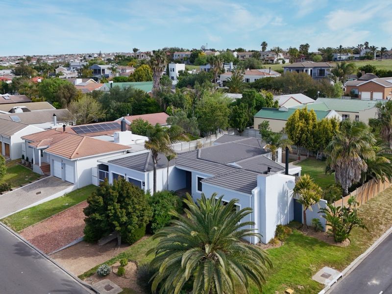 Aerial view of a residential property featuring a tiled roof, solar panels, and a paved driveway within a suburban neighborhood setting.